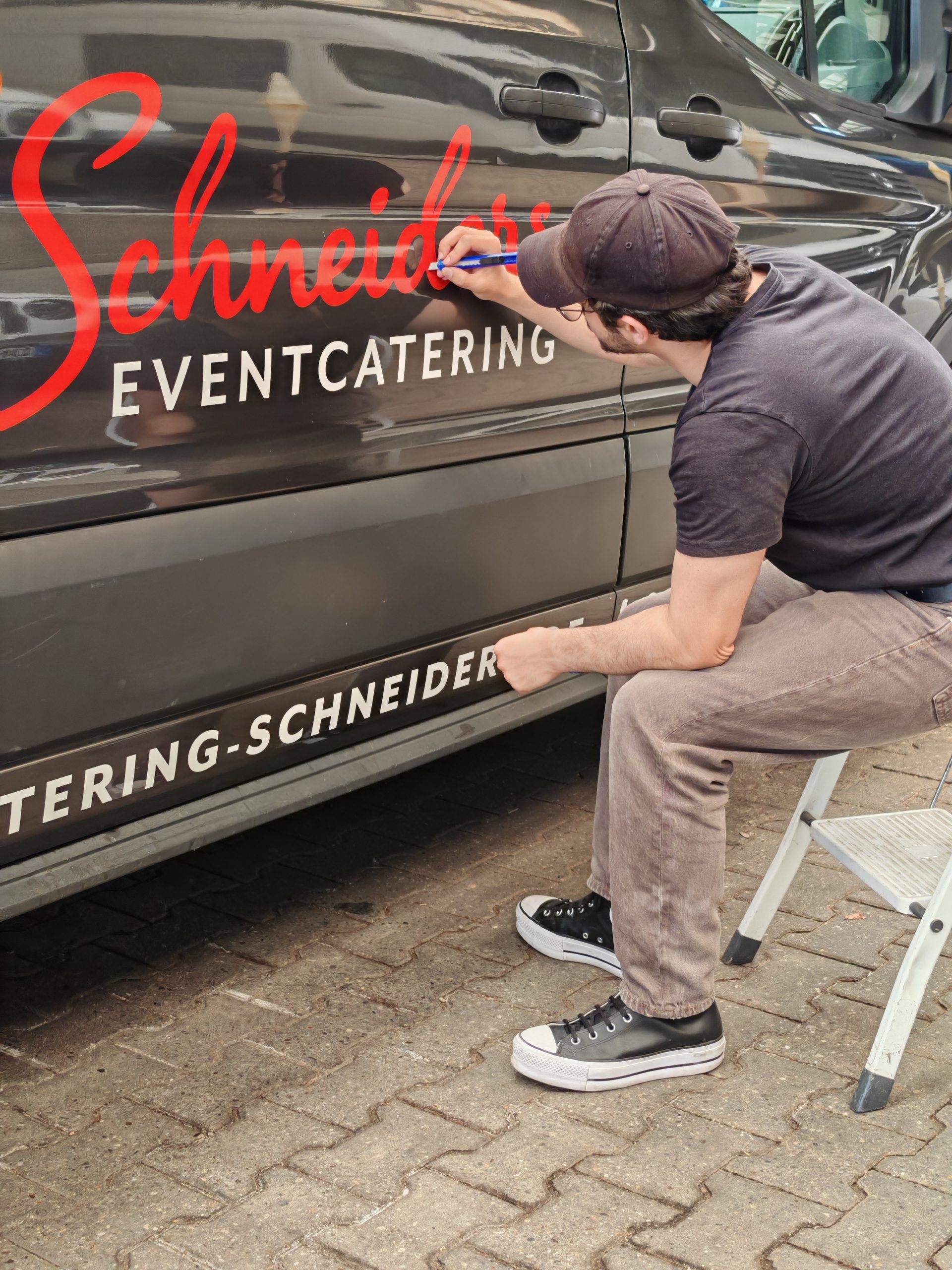 Montage einer Fahrzeugbeschriftung für Schneiders Eventcatering